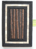 Black volcanic scoria finish wall plaque with travertine tile insert and aged mottle bamboo relief